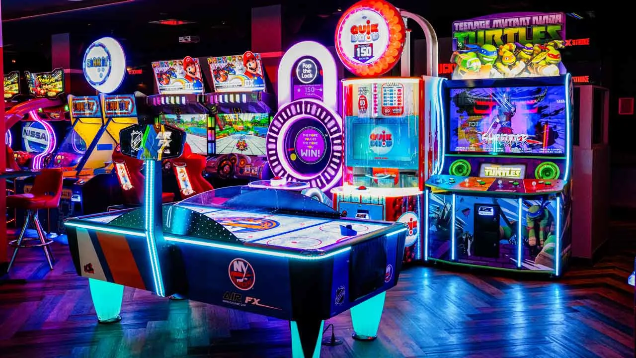 Arcade games including air hockey, Mario Kart, and Teenage Mutant Ninja Turtles lit up in neon at Lucky Strike Times Square