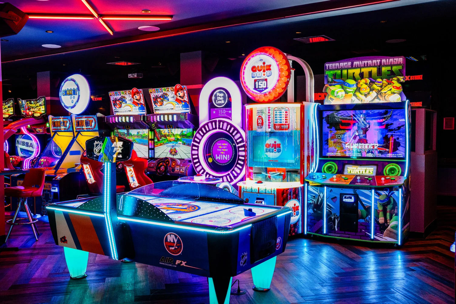 Arcade games including air hockey, Mario Kart, and Teenage Mutant Ninja Turtles lit up in neon at Lucky Strike Times Square
