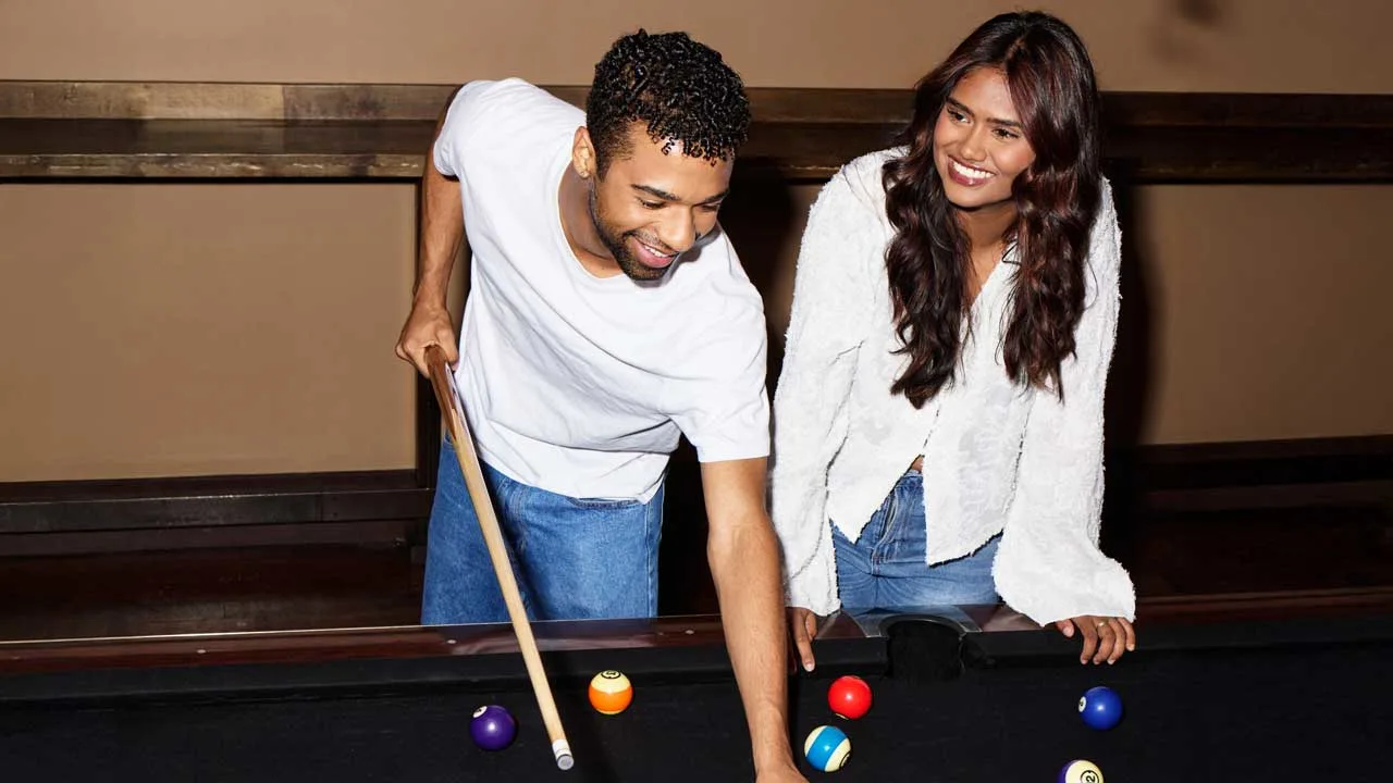 A couple playing billiards and pool at a Lucky Strike.