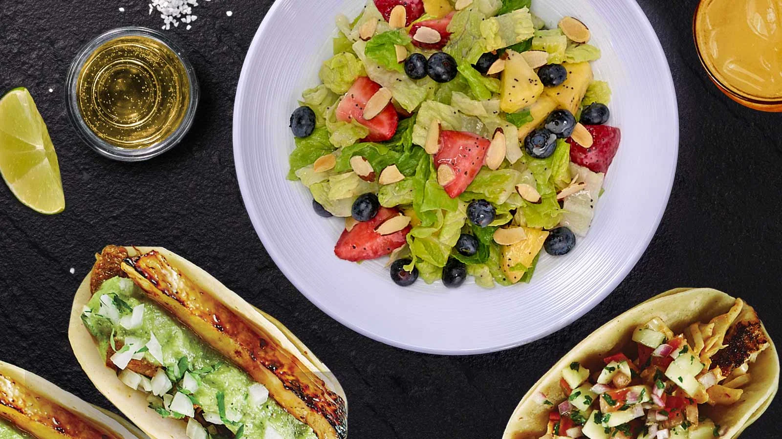 Strawberry poppy salad, sitting next to tacos and dipping sauces