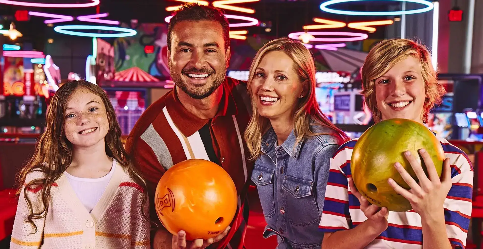 Family of four with a bowling alley arcade in the background.