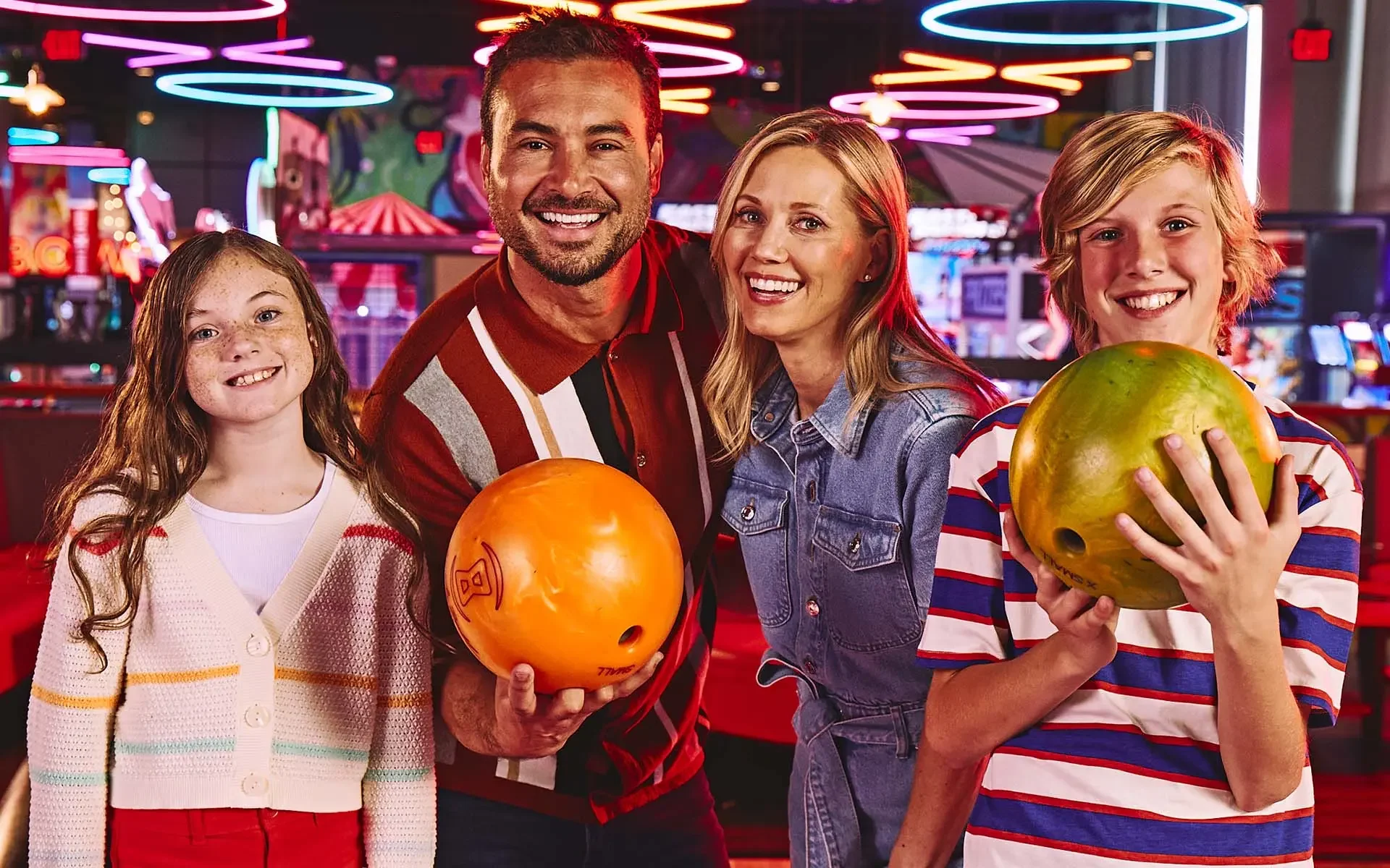 Family of four with a bowling alley arcade in the background.