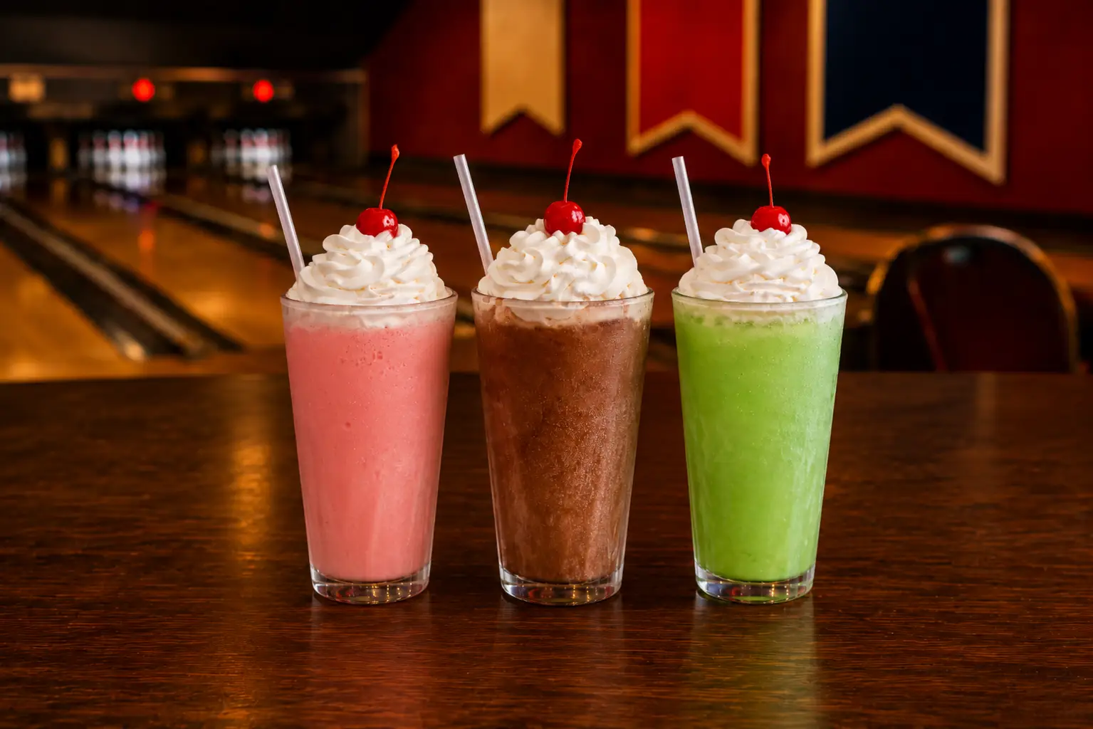 Premium dirty soda trio featuring Cherry Lime, Vanilla Dr. Pepper, and Sour Apple flavors served at bowling center with lanes visible in background.