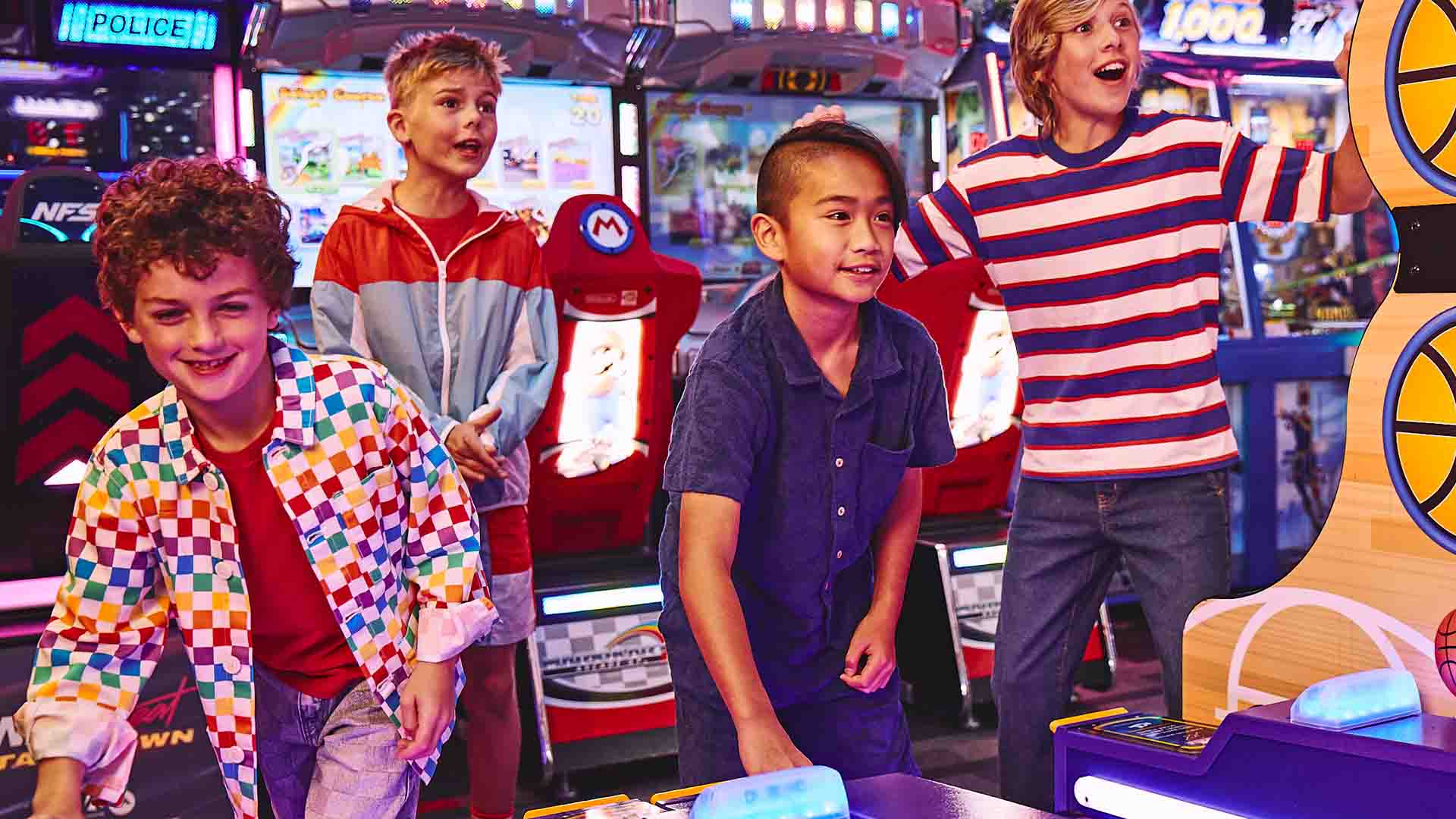 Four kids playing skee-ball and acrcade games