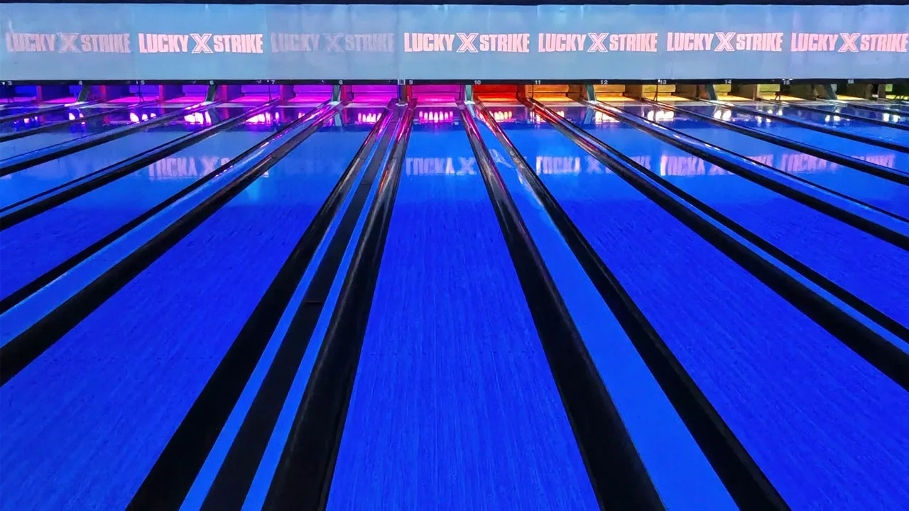 Beautiful bowling lanes with black lights and large TV screens above the lanes
