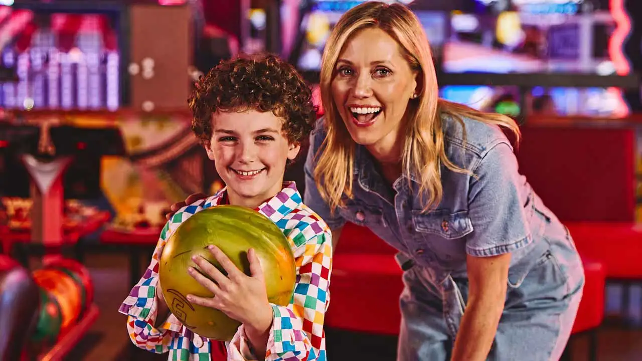 A mother and son posing for a picture at a Lucky Strike bowling center.