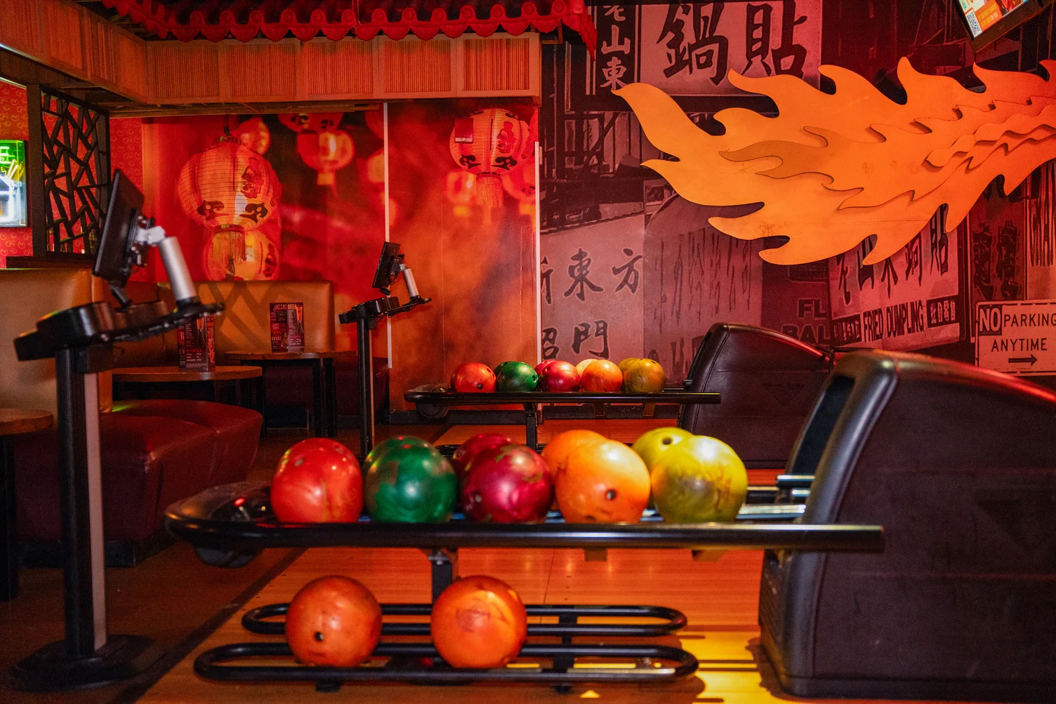 Bowling lane seating area with Chinatown-inspired mural decor and colorful bowling balls at Lucky Strike Times Square