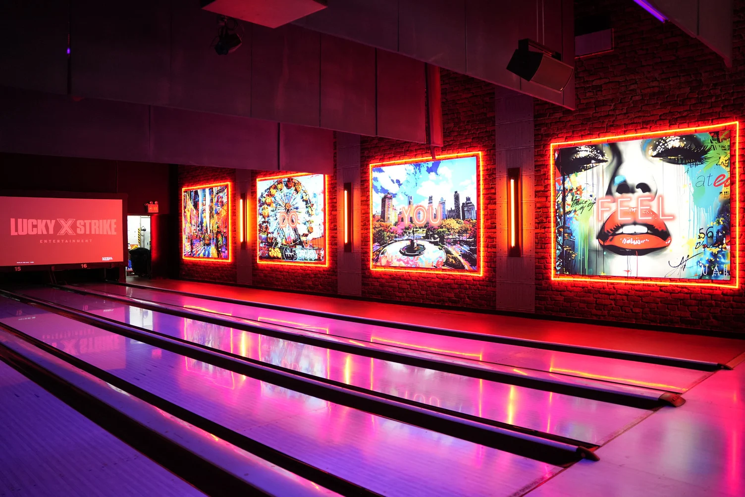 Beautiful bowling lanes under black lights with murals in the background.