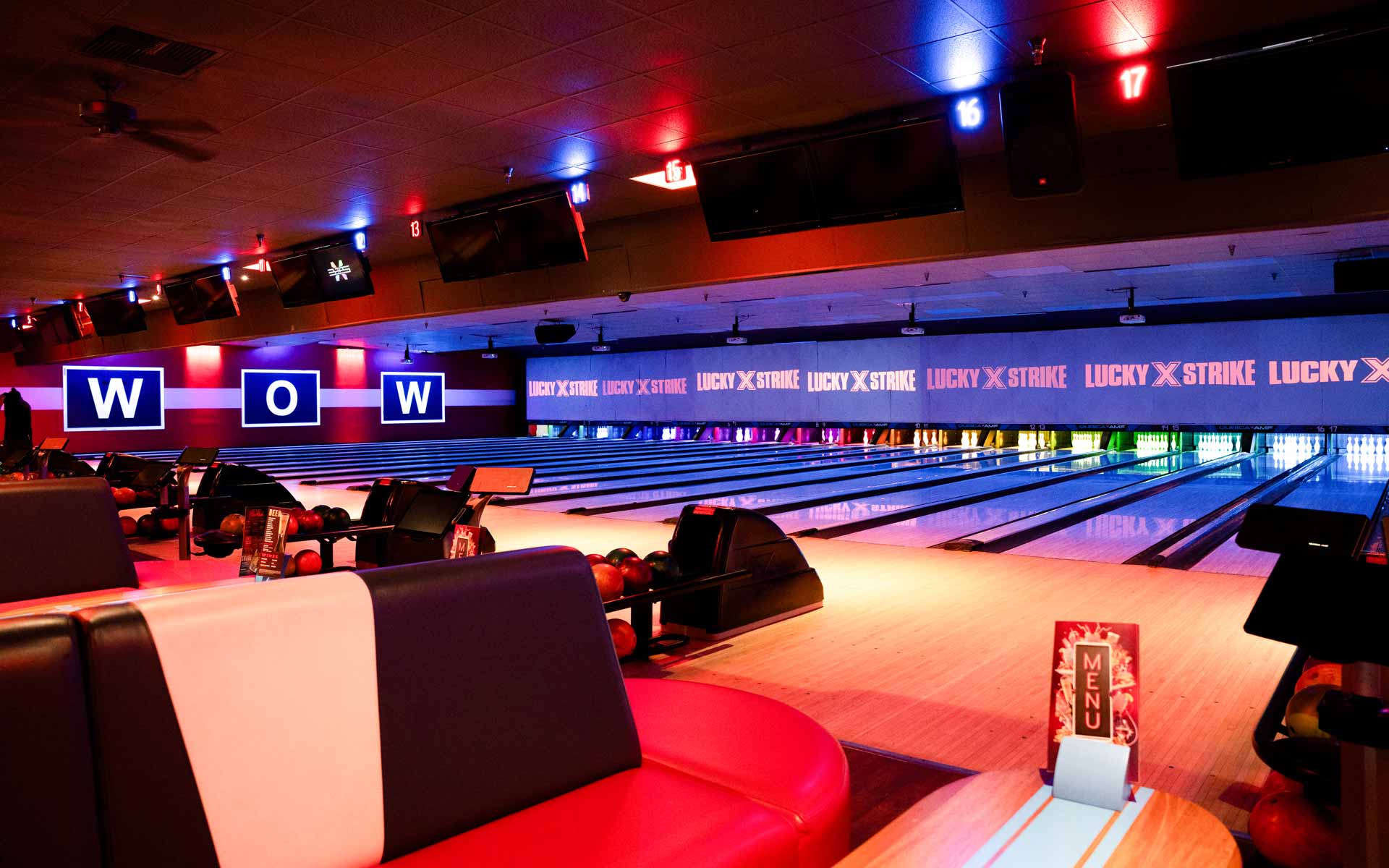 Neon-lit bowling lanes at Lucky Strike with lounge seating, scoring monitors, and colorful ambient lighting creating a high-energy nightlife atmosphere.