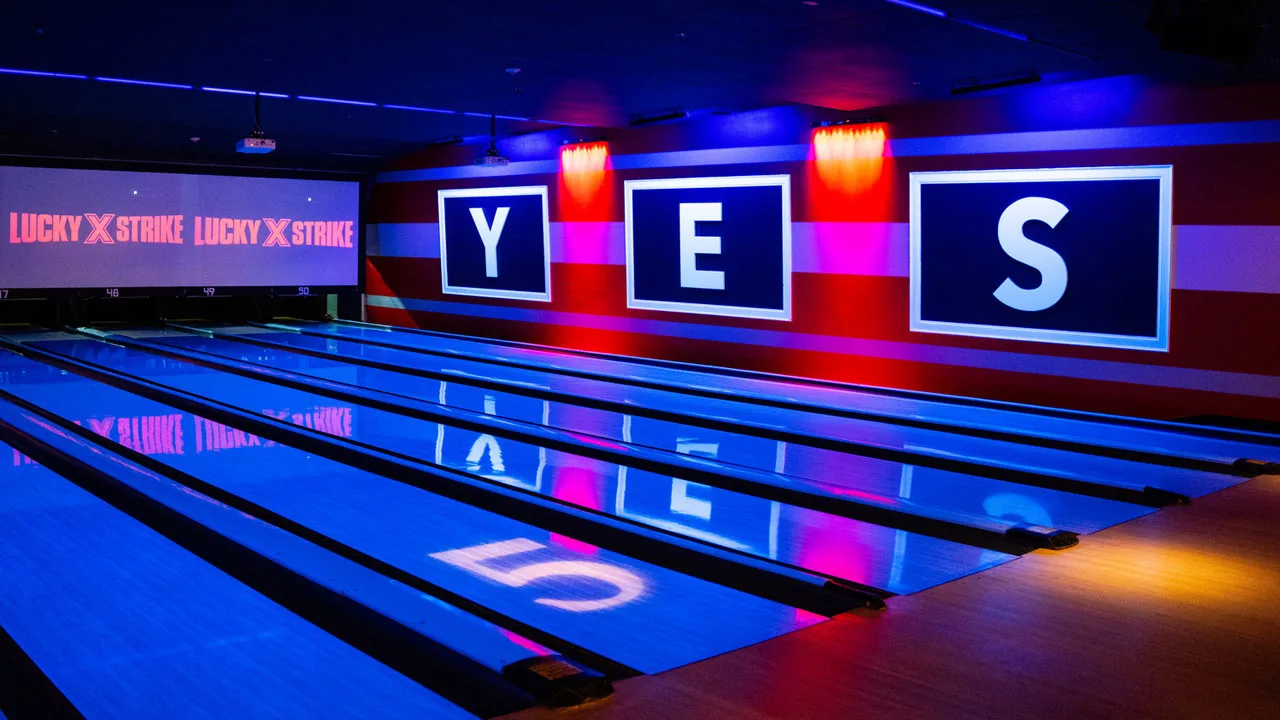 Beautiful bowling lanes with black lights and large TV screens above the lanes.