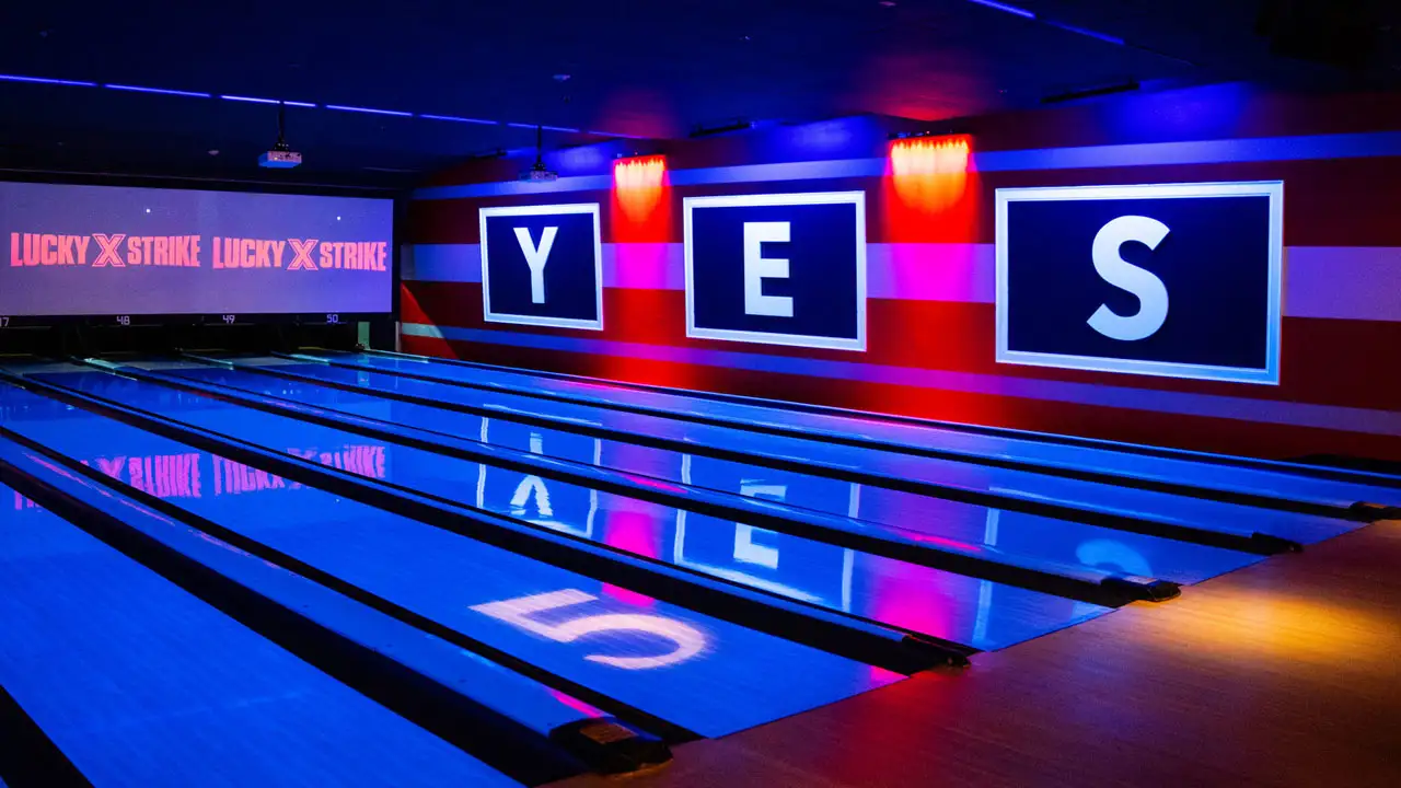 Beautiful bowling lanes with black lights and large TV screens above the lanes.