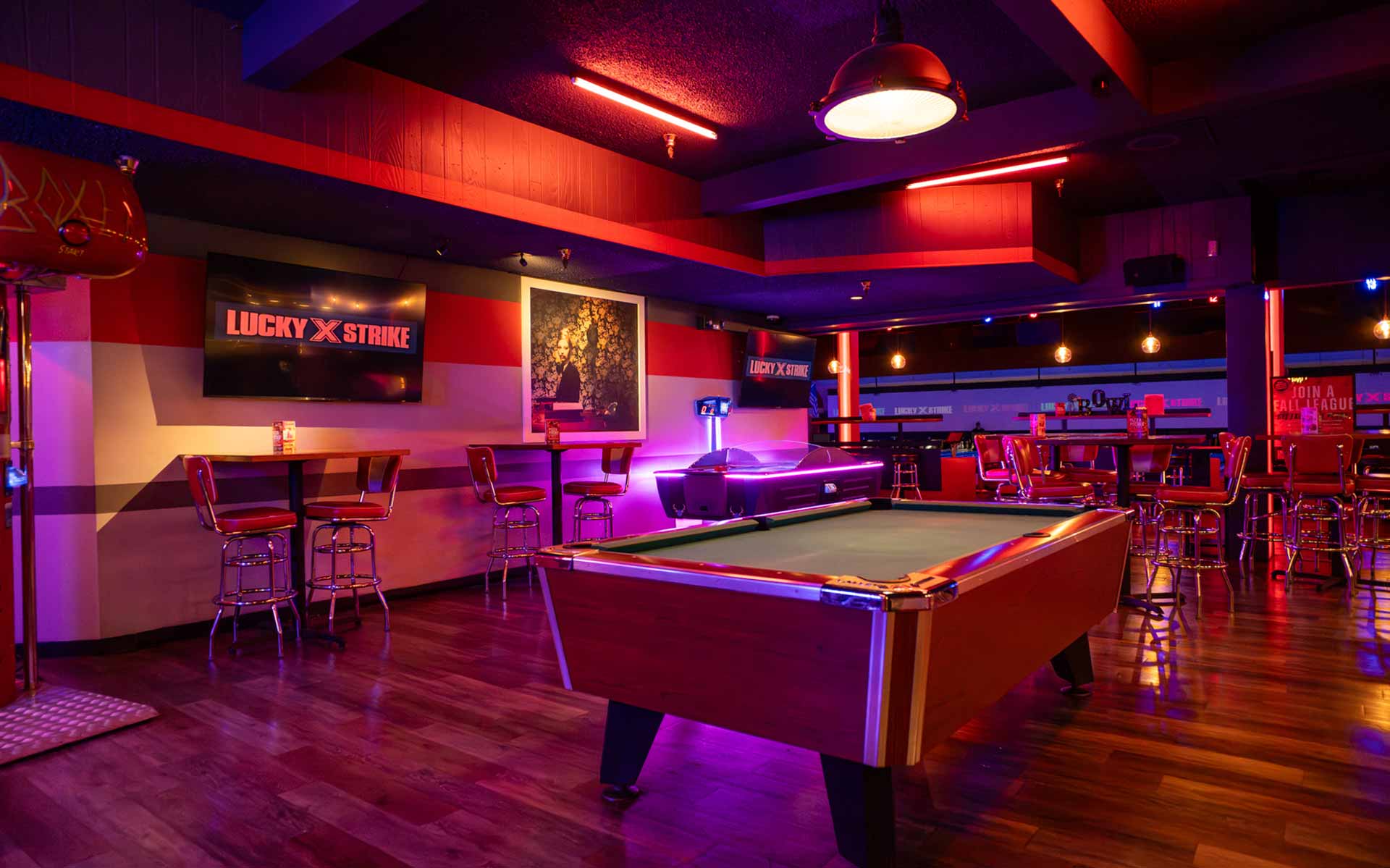 Upscale lounge at Lucky Strike with a pool table, high-top seating, and warm red and purple lighting for a social nightlife experience.