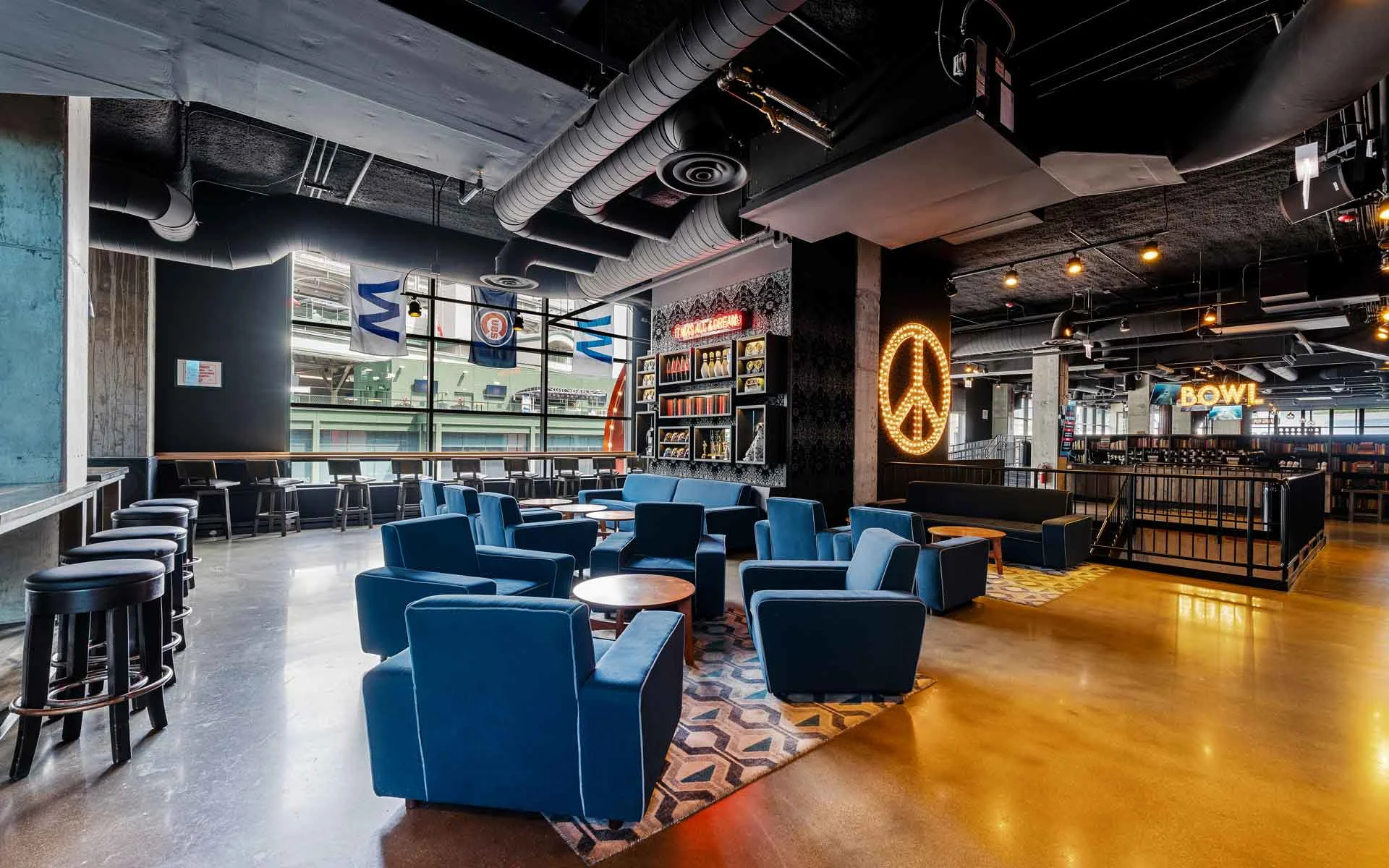 Stylish lounge seating area with armchairs, tables, and open views of bowling lanes inside a modern Lucky Strike venue.