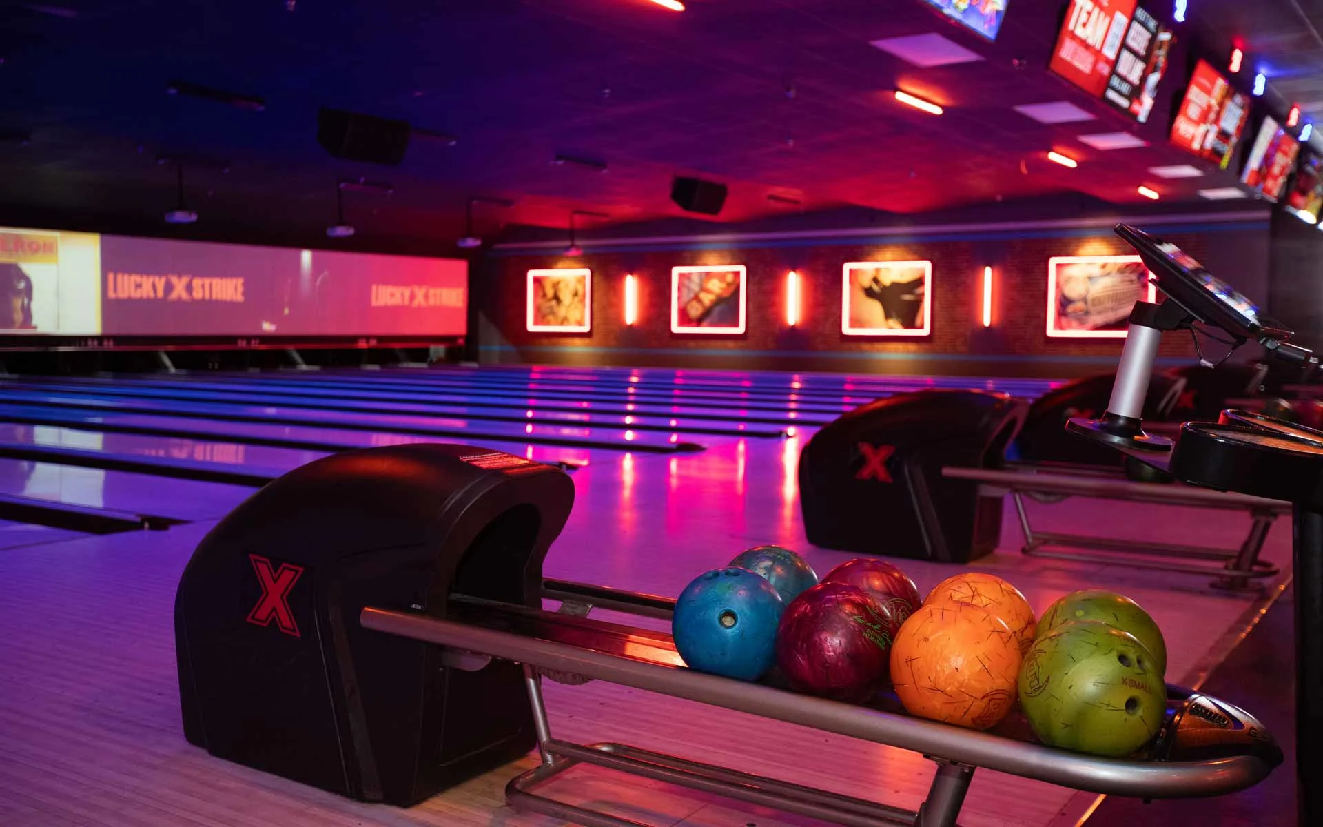 Lucky Strike bowling lanes with colorful bowling balls on ball return and neon-lit lanes in a premium bowling venue.