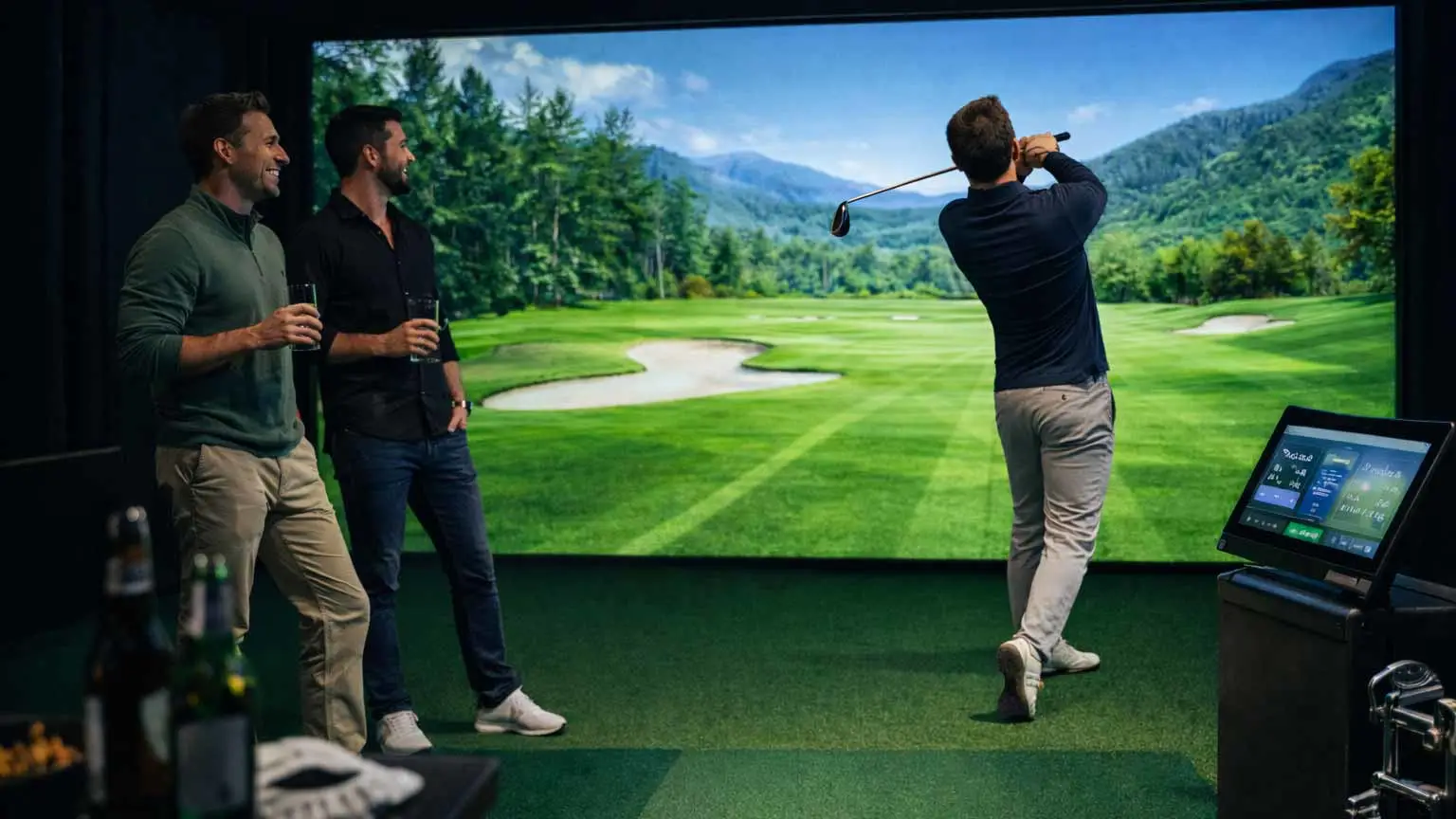 Group of friends enjoying a golf simulator, with one man swinging toward a large virtual course screen indoors.