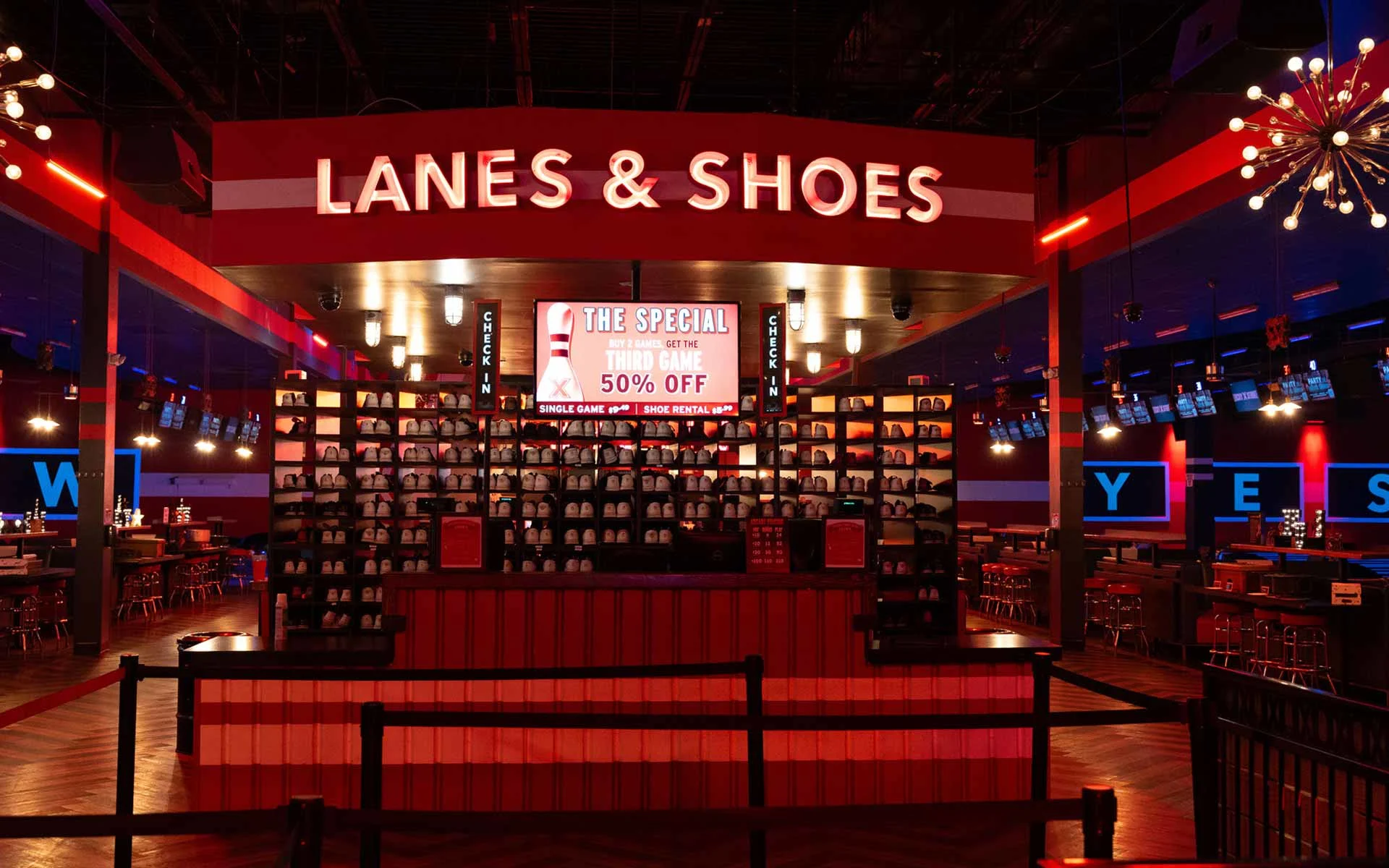 “Lanes & Shoes” rental counter with organized bowling shoes, check-in stations, and promotional signage inside Lucky Strike.