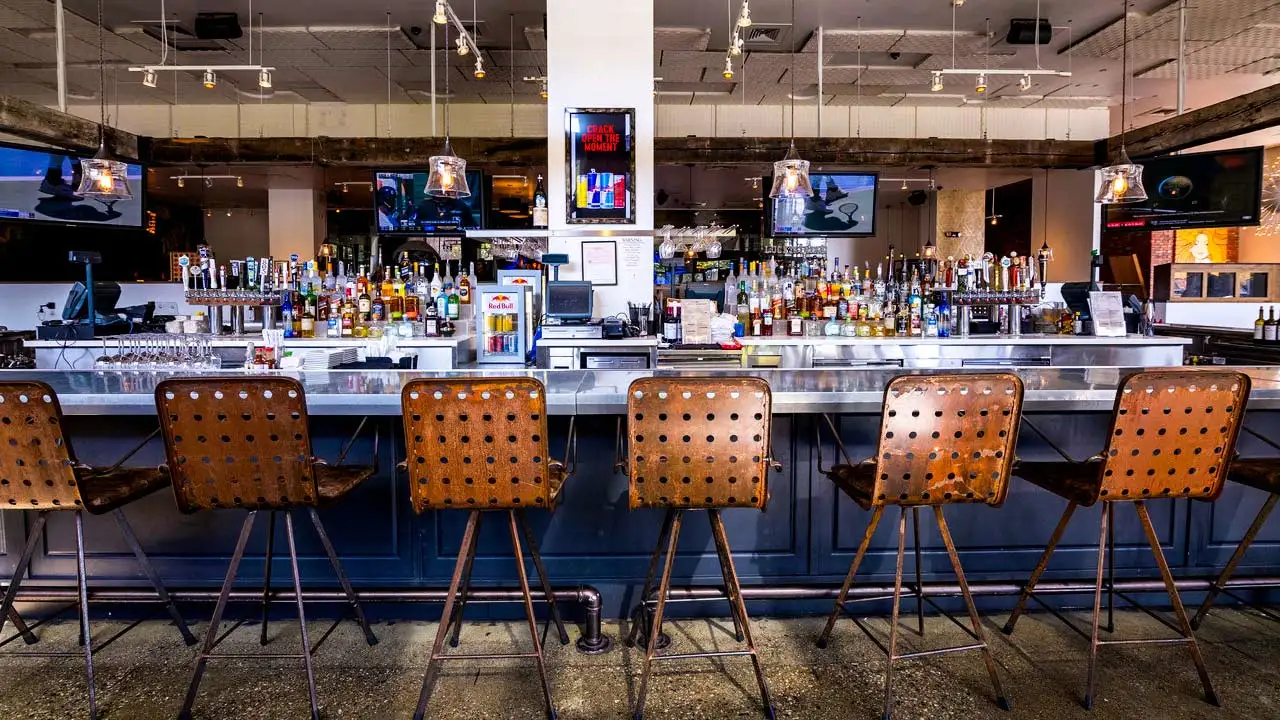 Beautiful, blue bar with lots of seating and TV screens above the bar