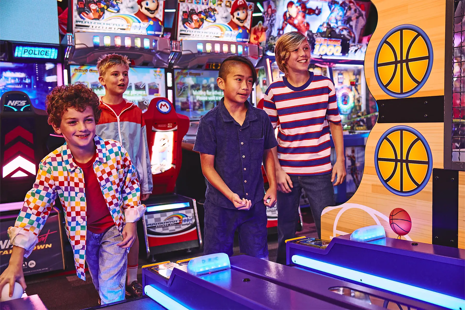 Group of kids playing arcade games and skeeball together, smiling and competing in a colorful, high-energy entertainment center with bright lights and interactive machines