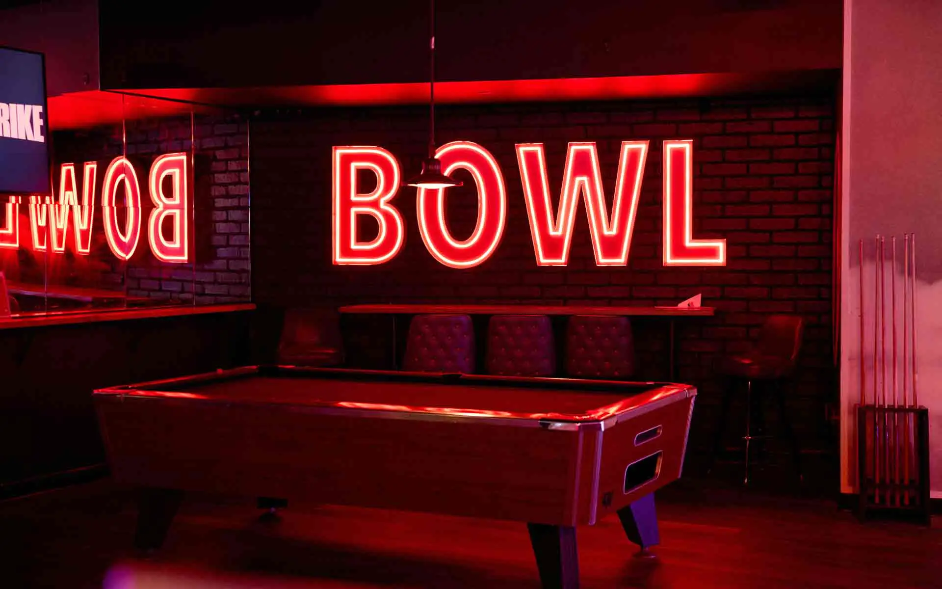 Pool table beneath red neon Bowl sign at Lucky Strike Los Angeles billiards lounge