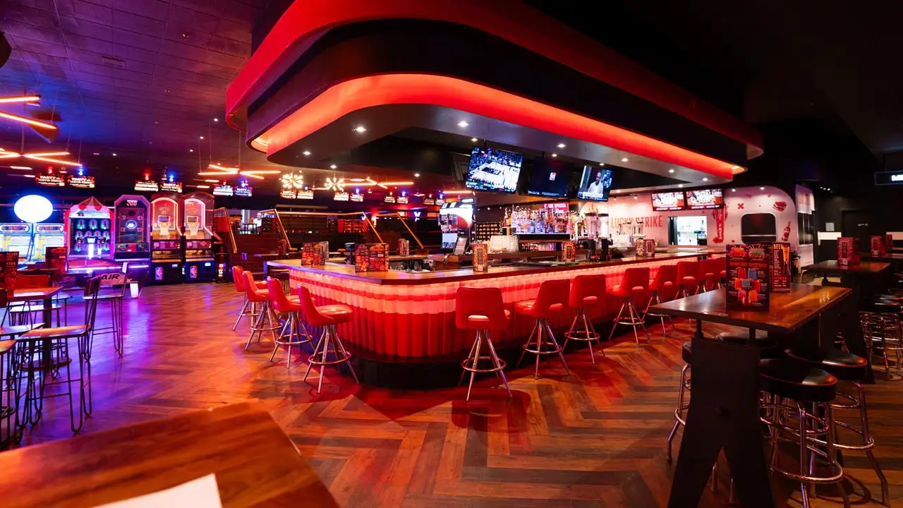 Large bar with lots of seating and large TV screens above the bar