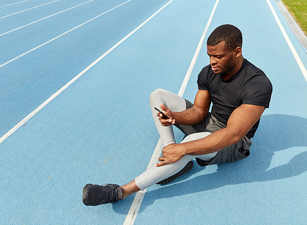 Man on blue track looking at phone