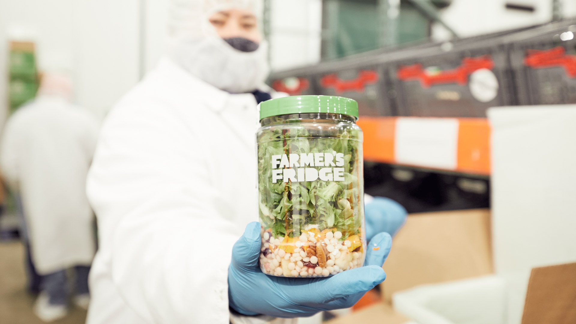 Farmer's Fridge worker holding up a Harvest Salad in a jar.