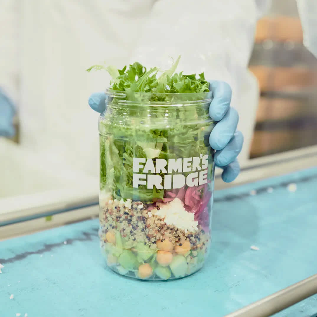 Image of a person holding a jar of salad.