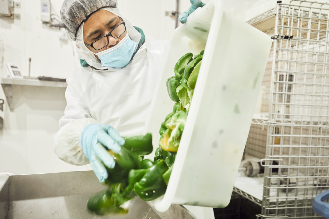 A Farmer's Fridge worker prepping bell peppers for our jars.