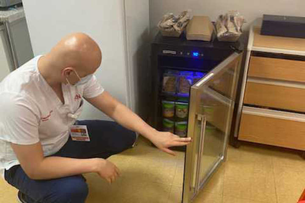 Man opening a refrigerator to grab a Farmer's Fridge jar 