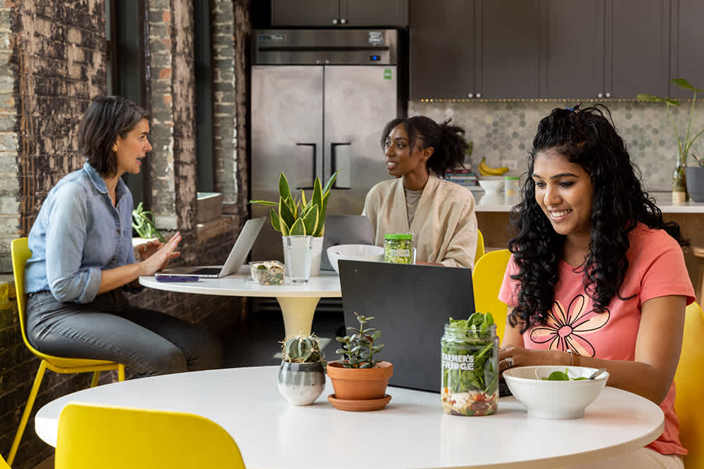 Employees sitting down at their workplace cafeteria with Farmer's Fridge meals