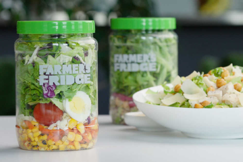 Two jars of Farmer's Fridge on a counter next to a bowl of salad