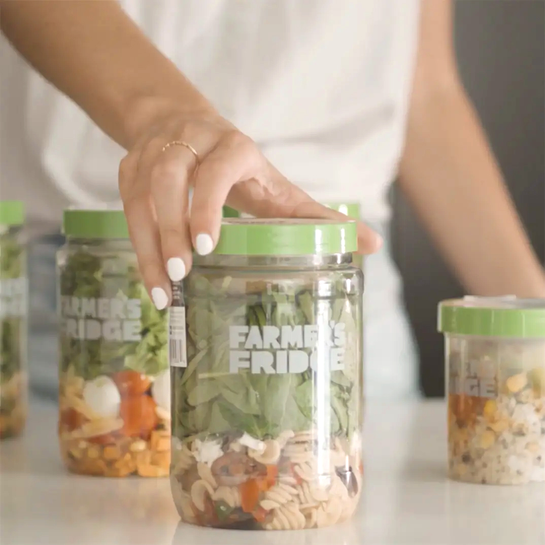 Image of a woman holding a jar with other jars in the background.