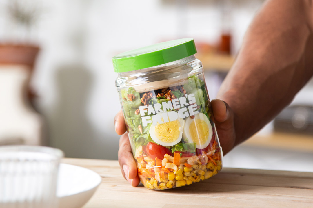 A person holding a Veggie Cobb Farmers Fridge salad in a jar.