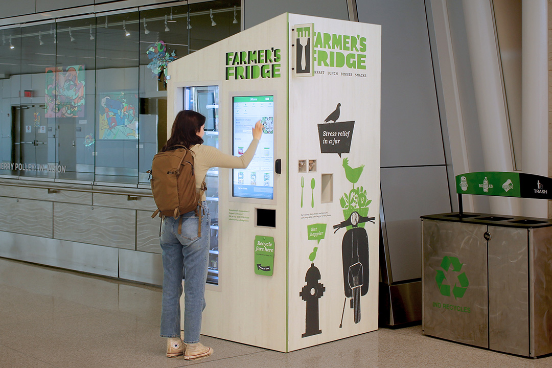 Woman using the touchscreen of a Farmer's Fridge.