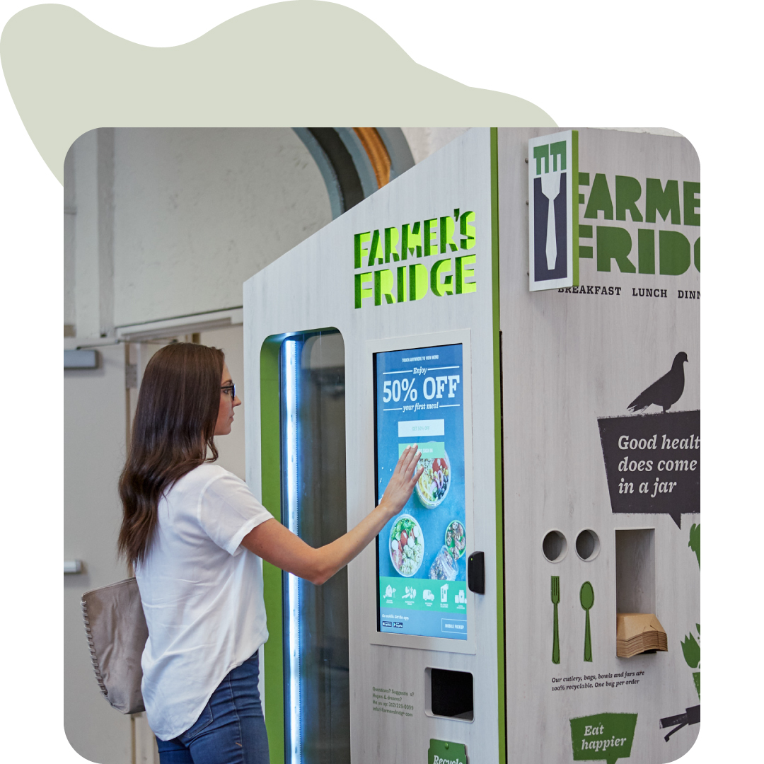 Image of a woman ordering a meal from a Farmer's Fridge vending machine.
