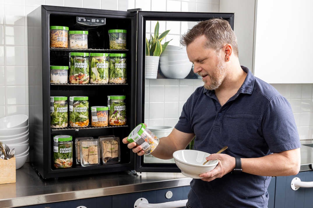 Image of man holding a jar in front of an office fridge