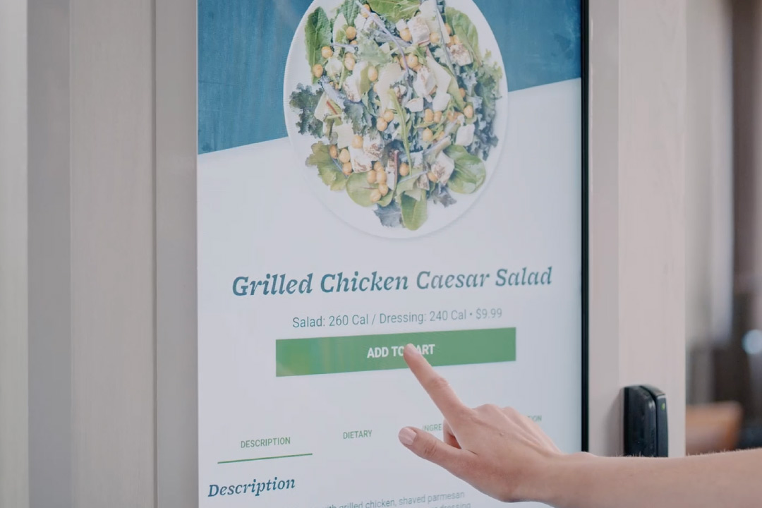 A person using a Farmer's Fridge touch screen to order food.