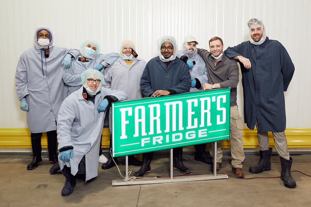 Image of Farmer's Fridge employees in front of an old sign.