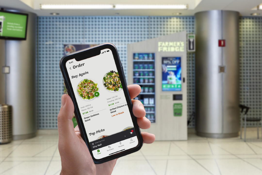 A person holding a phone that displays the Farmer's Fridge app.