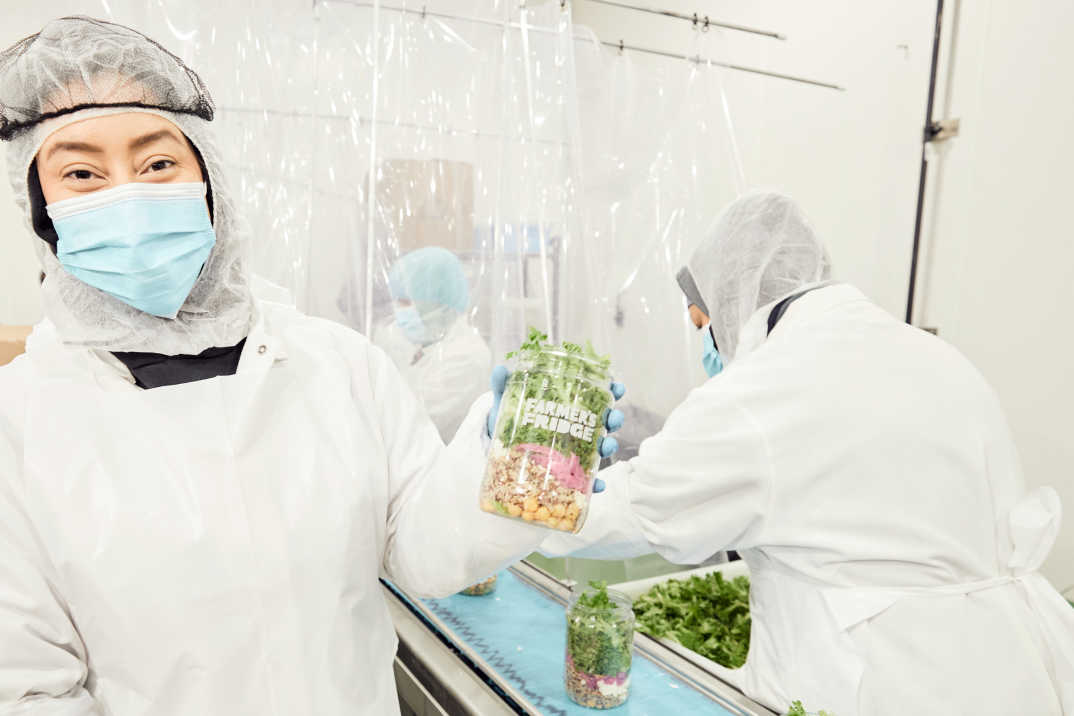 Workers in our factory holding up a salad from the assembly line. 