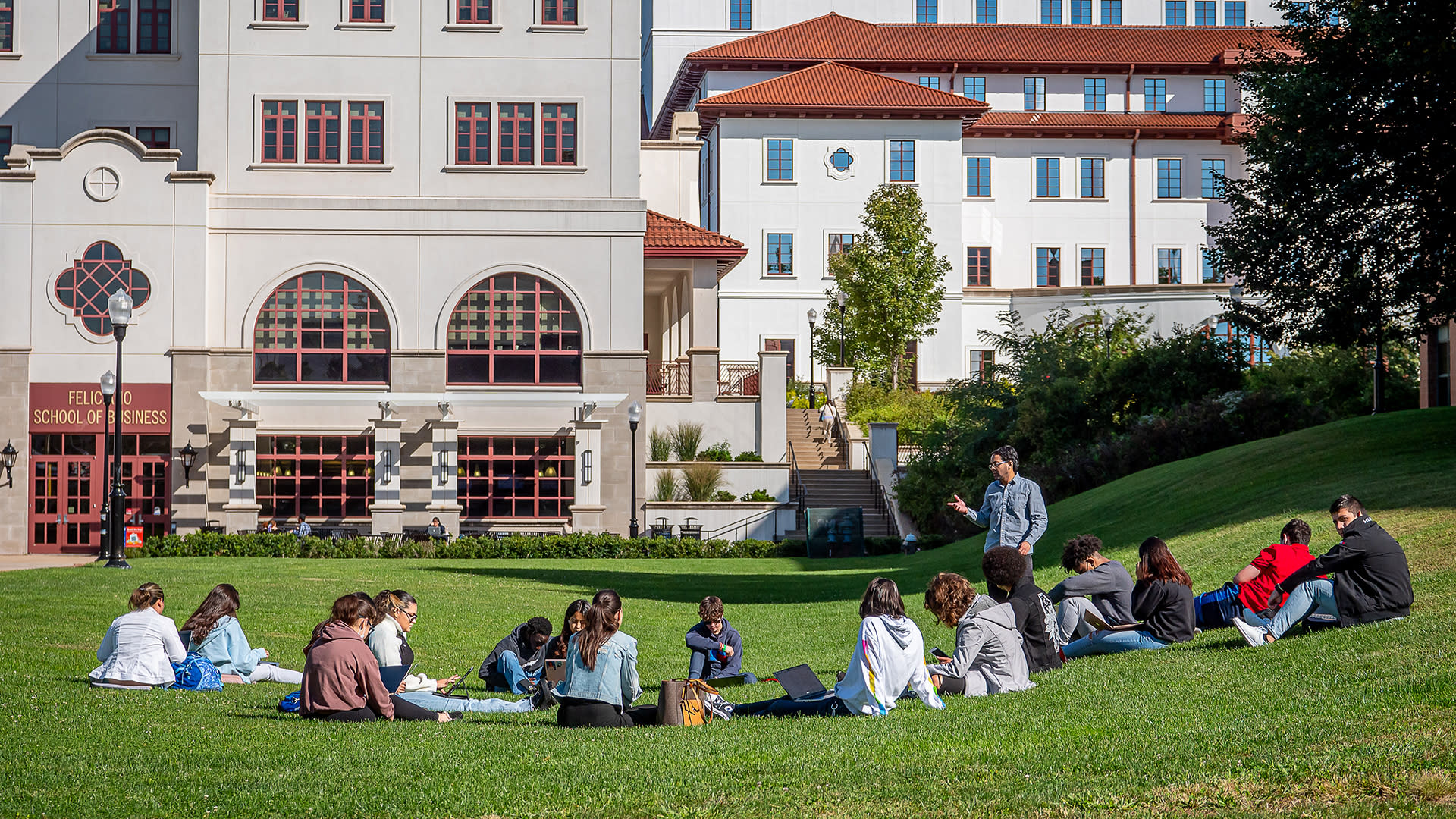 Image of students sitting in grass in front of Montclair State University building.