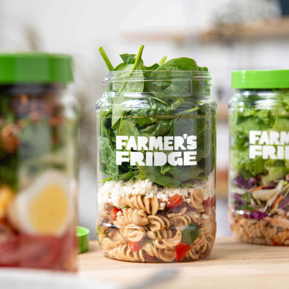 A greek salad in a jar next to two other salads.