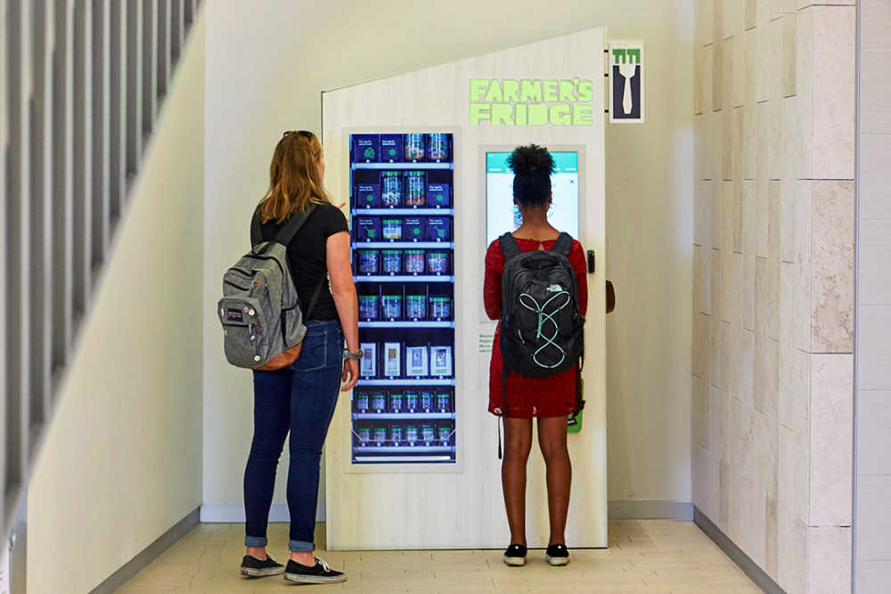 Two students standing in front of a Farmer's Fridge.