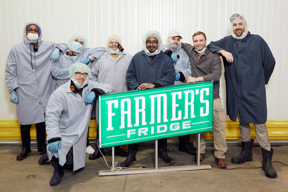 The Farmer's Fridge team standing behind a sign.