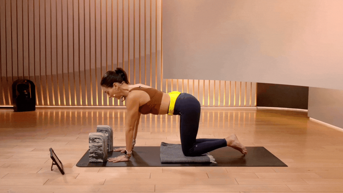 Peloton instructor Mariana Fernández demonstrates a modified Chaturanga Dandasana on her knees with blocks during a yoga class.