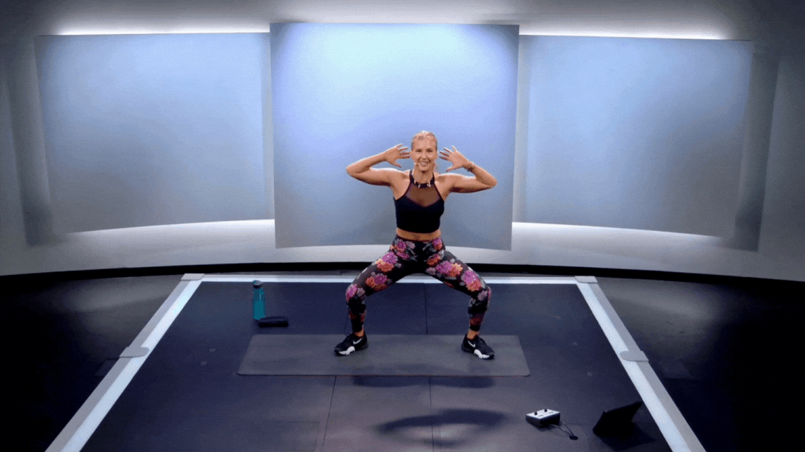Peloton instructor Rebecca Kennedy demonstrates a sumo side bend standing core exercise