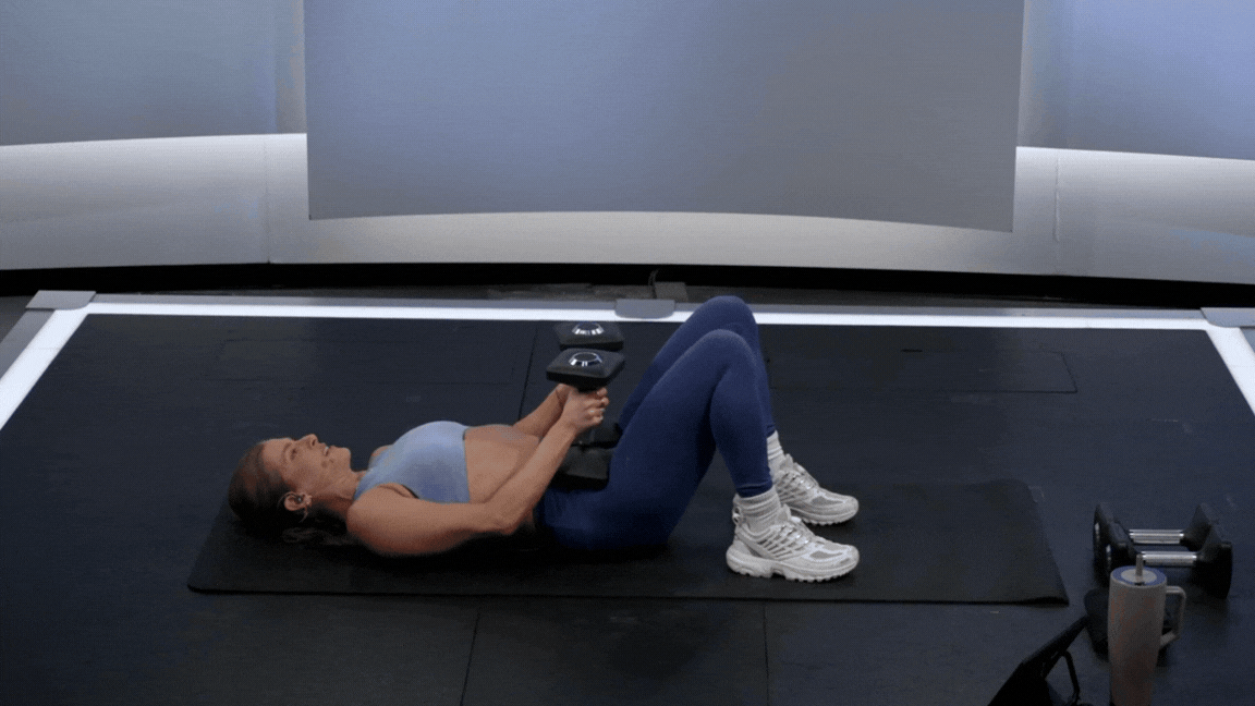 Peloton instructor Rebecca Kennedy demonstrates a weighted glute bridge dumbbell leg exercise.