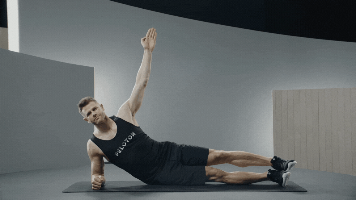 Peloton instructor Andy Speer demonstrates a forearm side plank warm-up exercise.