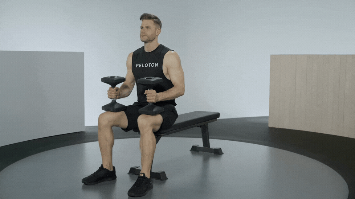 Peloton instructor Andy Speer demonstrates a flat bench dumbbell chest press as a chest-muscle building exercise 
