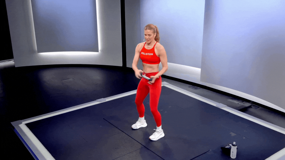 Peloton instructor Rebecca Kennedy demonstrates a standing dumbbell Russian twist core exercise